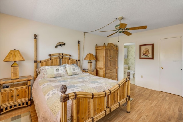 bedroom with ceiling fan, connected bathroom, a textured ceiling, and wood finished floors