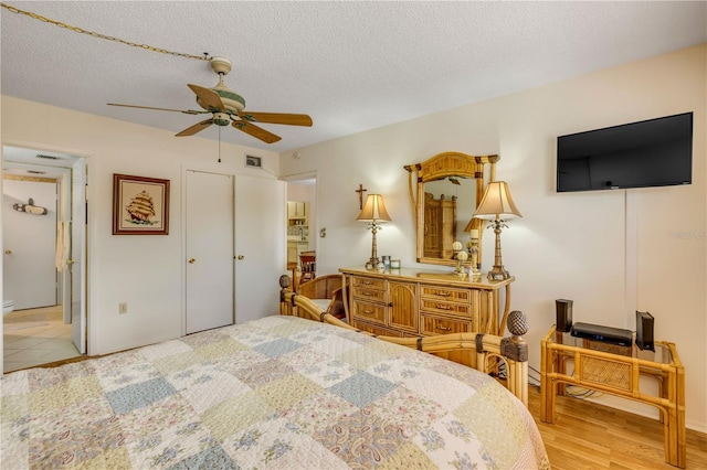 bedroom with a textured ceiling, wood finished floors, visible vents, and a ceiling fan