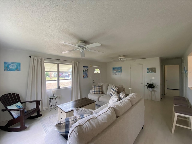 living room with a textured ceiling, light wood finished floors, and a ceiling fan