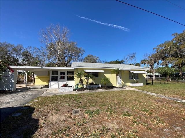 back of house with a carport, aphalt driveway, entry steps, fence, and a lawn