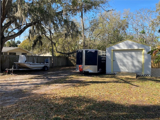 view of yard featuring a detached garage, fence, and an outdoor structure