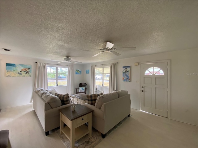 living room with a textured ceiling, ceiling fan, and visible vents