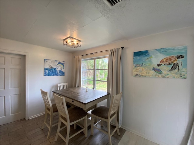 dining room featuring visible vents, baseboards, and wood finished floors