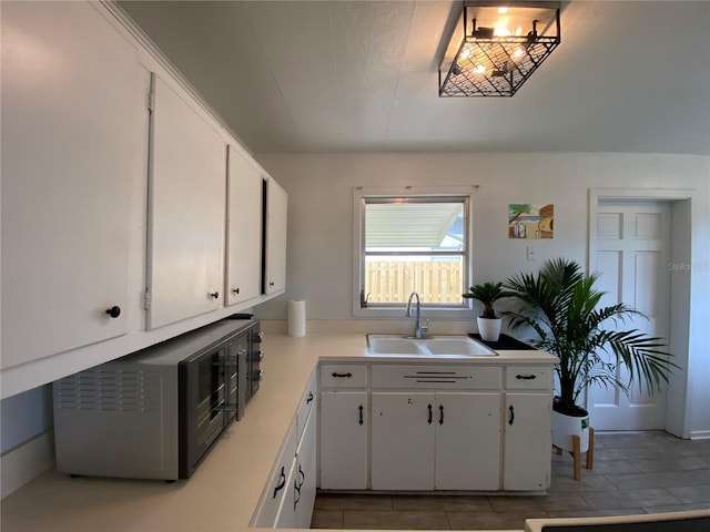 kitchen with a sink, light countertops, and white cabinetry