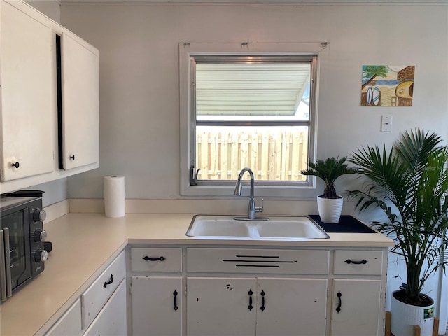 kitchen with a sink, light countertops, and white cabinetry