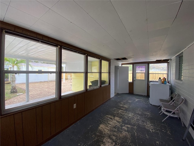unfurnished sunroom featuring wooden walls and washer / dryer