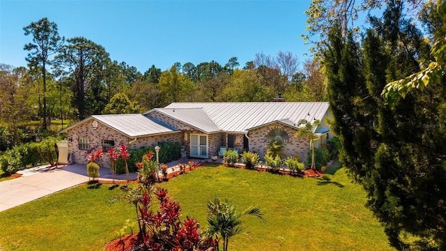 view of front of property featuring brick siding, a front yard, metal roof, driveway, and a standing seam roof