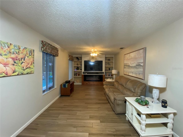 living area featuring visible vents, wood finished floors, baseboards, and ceiling fan