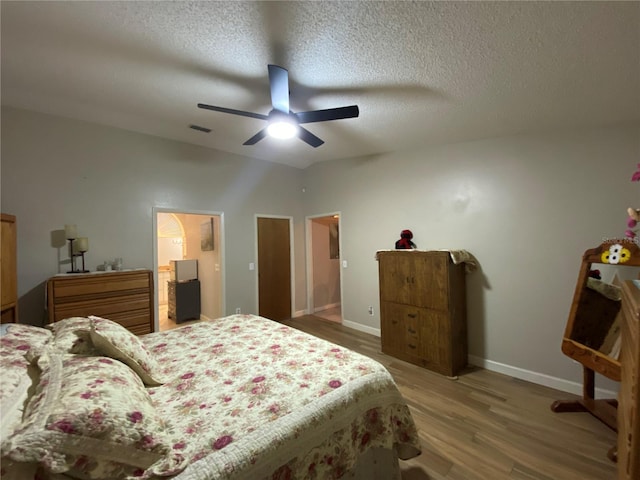 bedroom featuring visible vents, baseboards, light wood-type flooring, a textured ceiling, and a ceiling fan