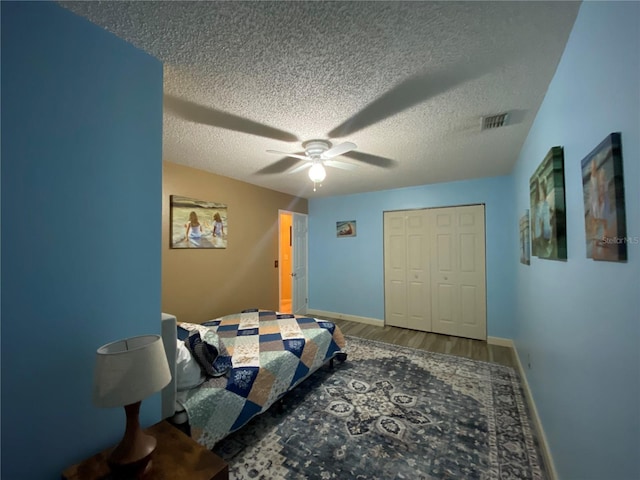 bedroom with visible vents, a textured ceiling, ceiling fan, and wood finished floors