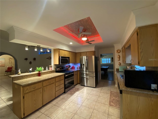 kitchen with a peninsula, light tile patterned floors, arched walkways, and appliances with stainless steel finishes