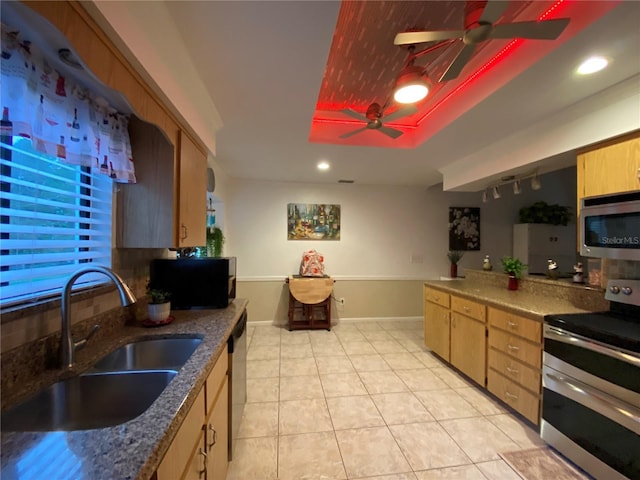 kitchen with baseboards, ceiling fan, light tile patterned floors, appliances with stainless steel finishes, and a sink