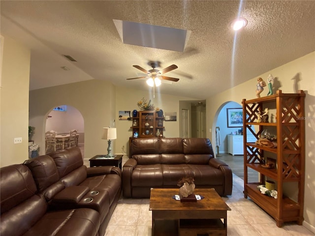 living area with visible vents, ceiling fan, light tile patterned floors, arched walkways, and a textured ceiling