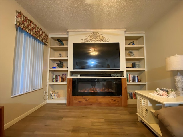 living area featuring a glass covered fireplace, wood finished floors, and a textured ceiling