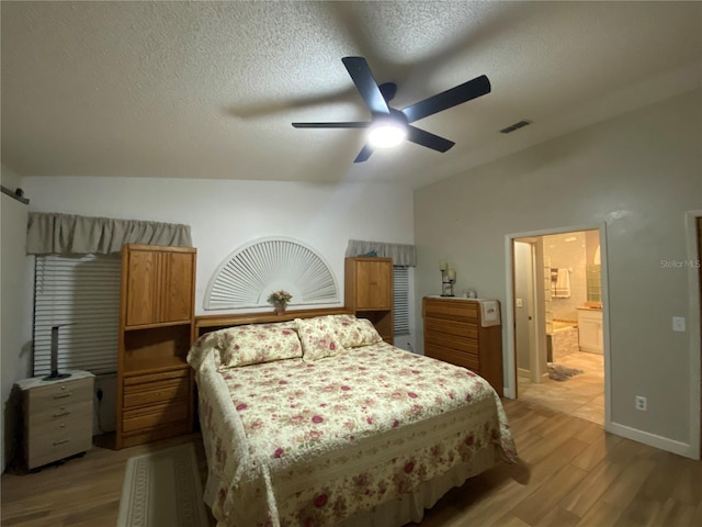 bedroom featuring visible vents, lofted ceiling, a textured ceiling, and light wood-style flooring