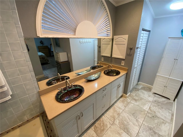 bathroom featuring double vanity, ornamental molding, baseboards, and a sink