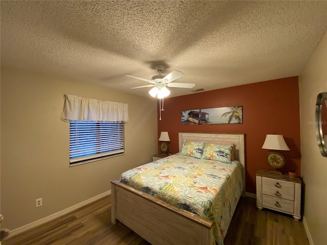 bedroom with ceiling fan, baseboards, a textured ceiling, and wood finished floors