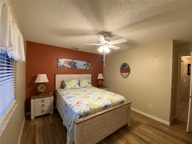 bedroom featuring visible vents, baseboards, wood finished floors, and a ceiling fan