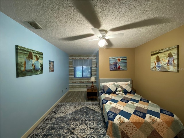 bedroom featuring visible vents, a textured ceiling, ceiling fan, and wood finished floors