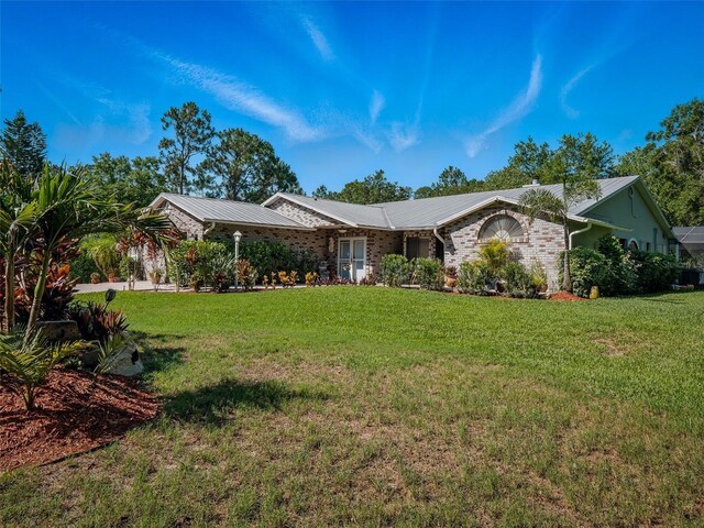 1370 Jane Lacey Ln, New Smyrna Beach, FL 32168 - ranch-style house with a front yard, metal roof, and brick siding