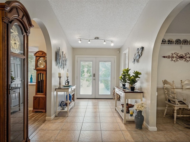 1370 Jane Lacey Ln, New Smyrna Beach, FL 32168 - entrance foyer featuring french doors, light tile patterned flooring, arched walkways, a textured ceiling, and baseboards