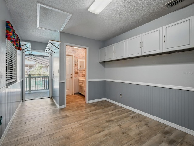 1370 Jane Lacey Ln, New Smyrna Beach, FL 32168 - spare room featuring attic access, wainscoting, light wood-style flooring, a textured ceiling, and baseboards