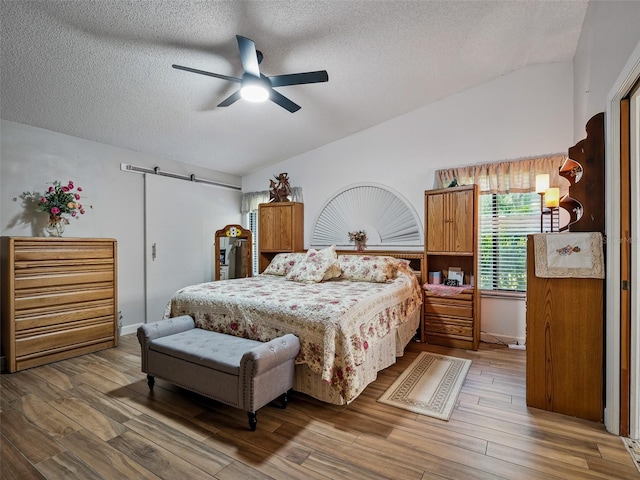 1370 Jane Lacey Ln, New Smyrna Beach, FL 32168 - bedroom featuring lofted ceiling, a textured ceiling, wood finished floors, a barn door, and ceiling fan