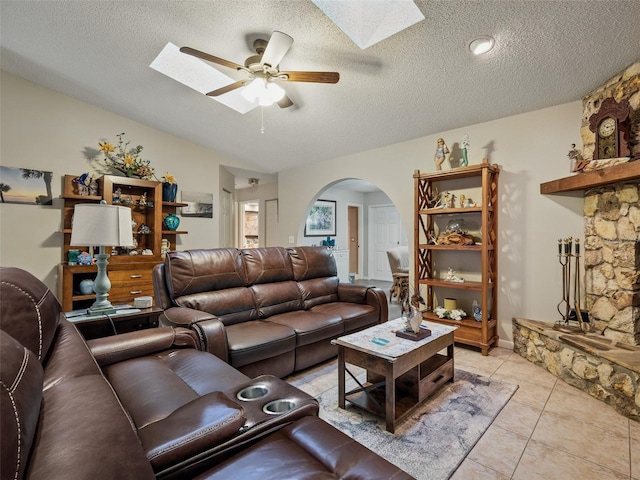 1370 Jane Lacey Ln, New Smyrna Beach, FL 32168 - living room featuring arched walkways, a ceiling fan, a skylight, a textured ceiling, and light tile patterned floors