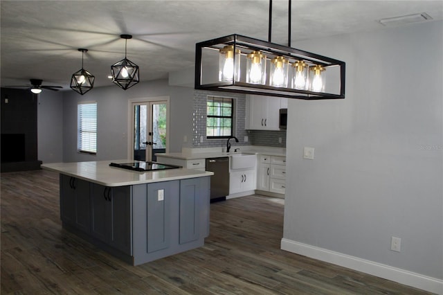 kitchen with dark wood-style flooring, black electric stovetop, visible vents, a sink, and dishwashing machine