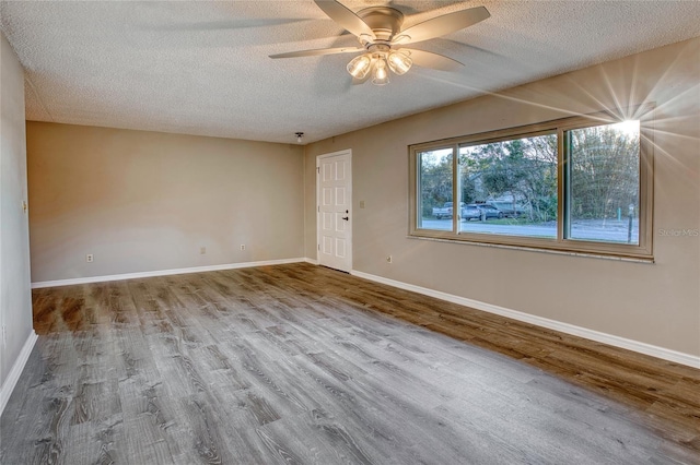 empty room featuring ceiling fan, a textured ceiling, baseboards, and wood finished floors