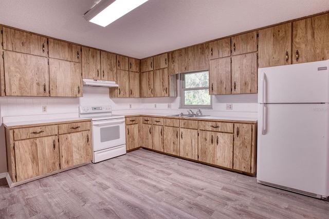 kitchen featuring white appliances, light wood-style flooring, light countertops, under cabinet range hood, and a sink