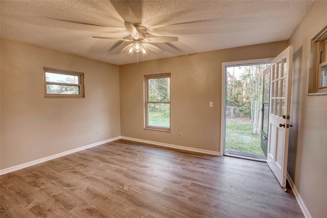 spare room with a textured ceiling, wood finished floors, and baseboards