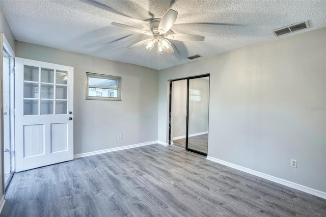 empty room with baseboards, wood finished floors, visible vents, and a ceiling fan