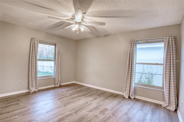 empty room with a ceiling fan, a textured ceiling, baseboards, and wood finished floors