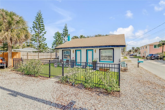 bungalow-style house with a fenced front yard and roof with shingles