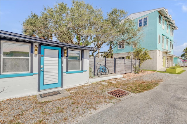 view of exterior entry featuring concrete block siding, fence, and stucco siding