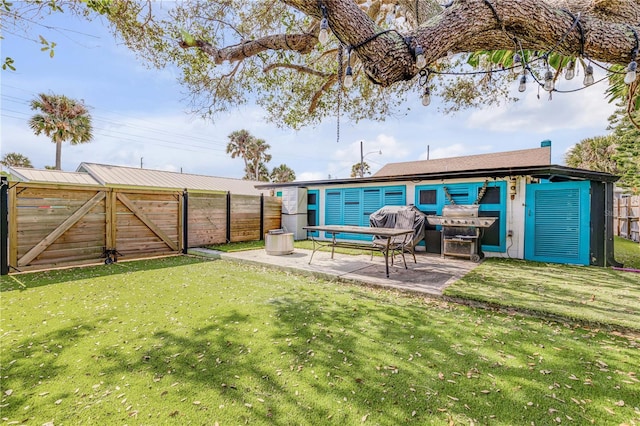 rear view of property featuring a yard, a fenced backyard, and a patio