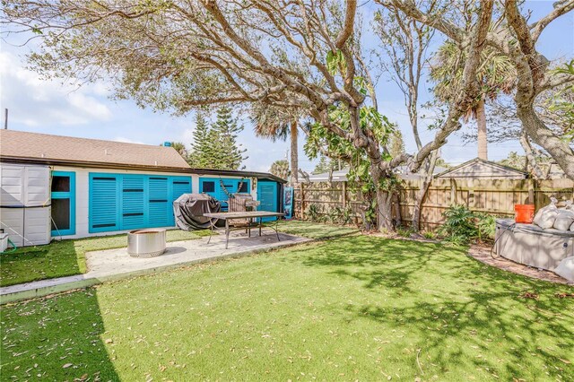 view of yard featuring a fenced backyard, a storage unit, an outdoor structure, and a patio