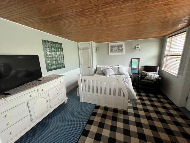 bedroom featuring dark colored carpet and wood ceiling