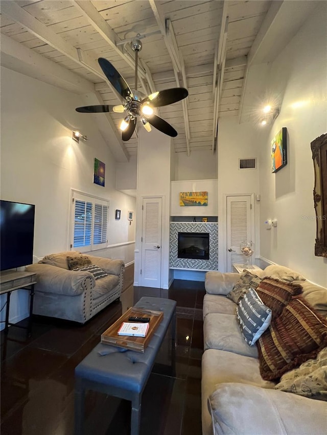 living area with beamed ceiling, wooden ceiling, a tile fireplace, and visible vents