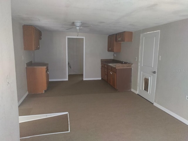 kitchen featuring ceiling fan, baseboards, and brown cabinetry