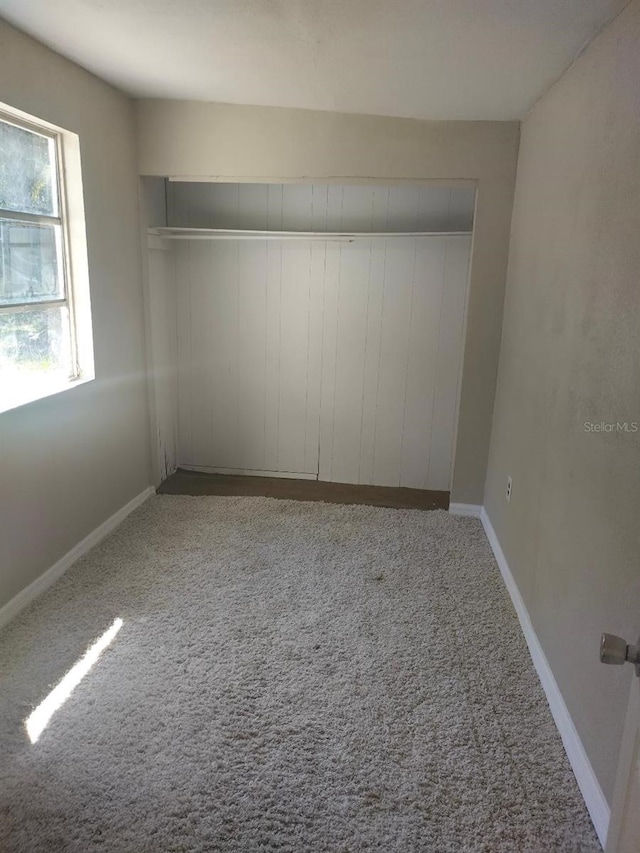 unfurnished room featuring carpet floors and baseboards