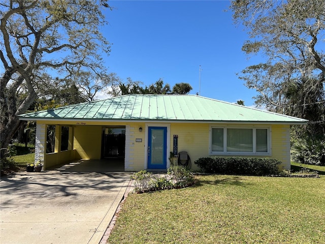 single story home featuring driveway, metal roof, a standing seam roof, a carport, and a front yard