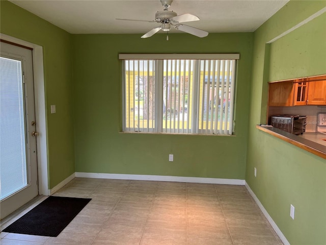 interior space featuring a ceiling fan, a toaster, and baseboards