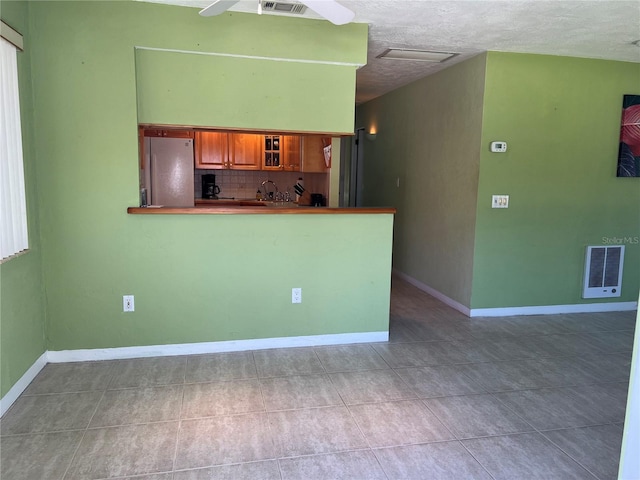 kitchen featuring light tile patterned floors, visible vents, backsplash, and freestanding refrigerator