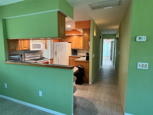 630 Yupon Ave, New Smyrna Beach, FL 32169 - kitchen with white appliances, light tile patterned floors, visible vents, baseboards, and a peninsula