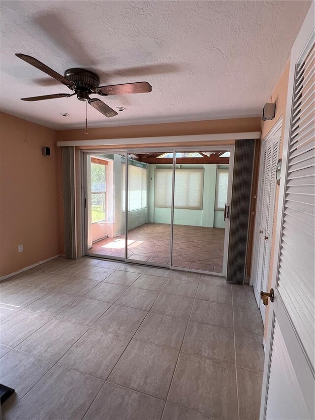 630 Yupon Ave, New Smyrna Beach, FL 32169 - unfurnished bedroom with access to exterior, tile patterned floors, a textured ceiling, and a ceiling fan