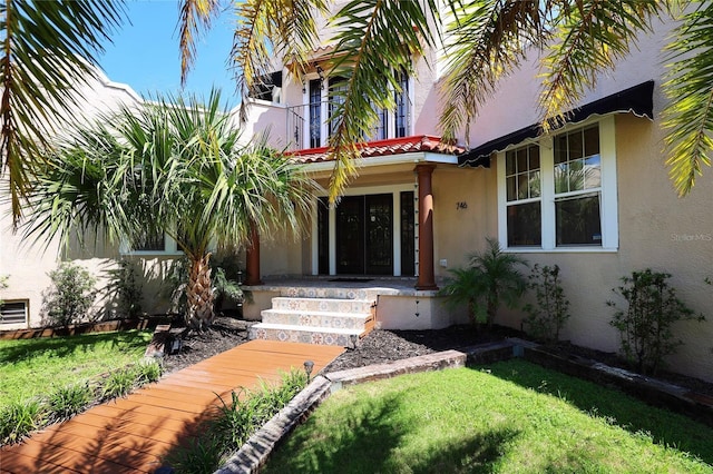 doorway to property featuring a lawn and stucco siding