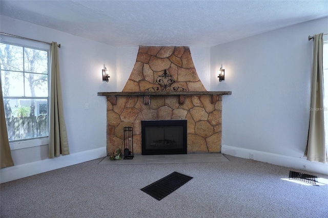 unfurnished living room with a stone fireplace, carpet, baseboards, and a textured ceiling