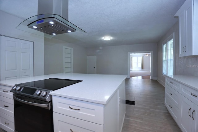 kitchen with a textured ceiling, a kitchen island, black / electric stove, white cabinets, and island range hood